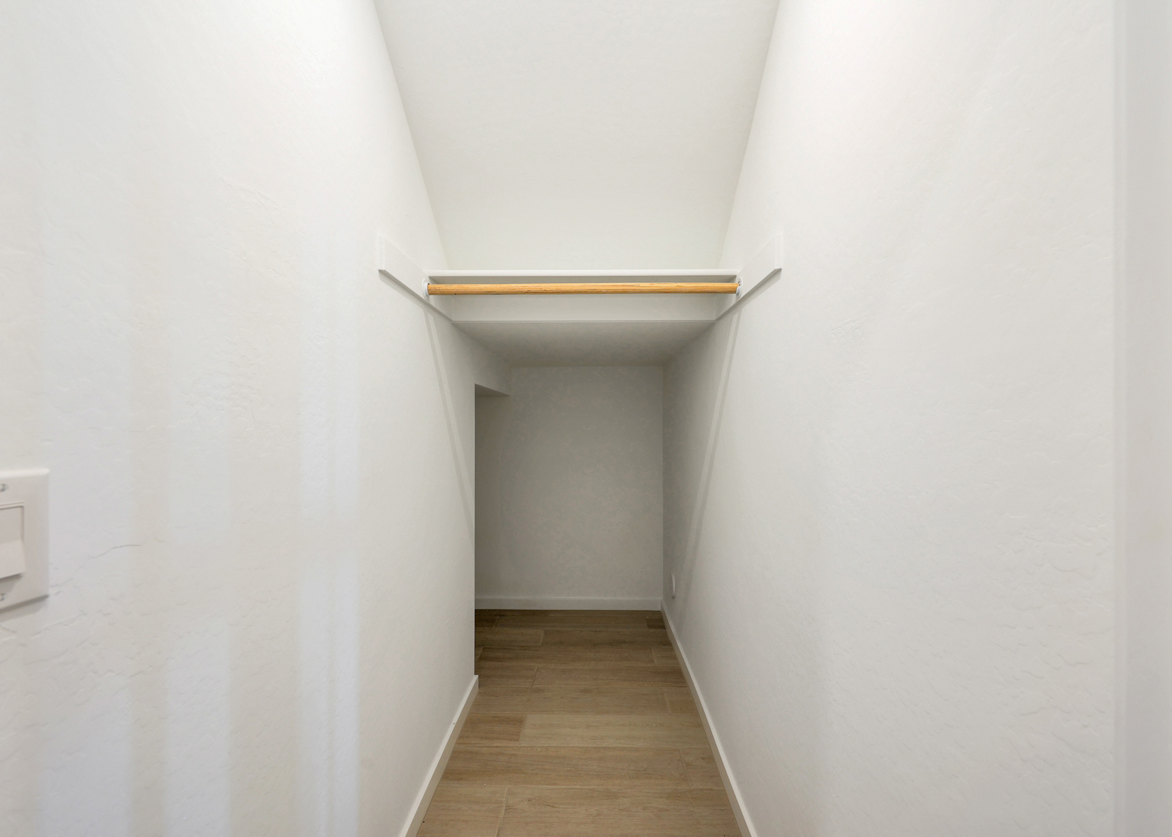A white room with a wooden shelf.