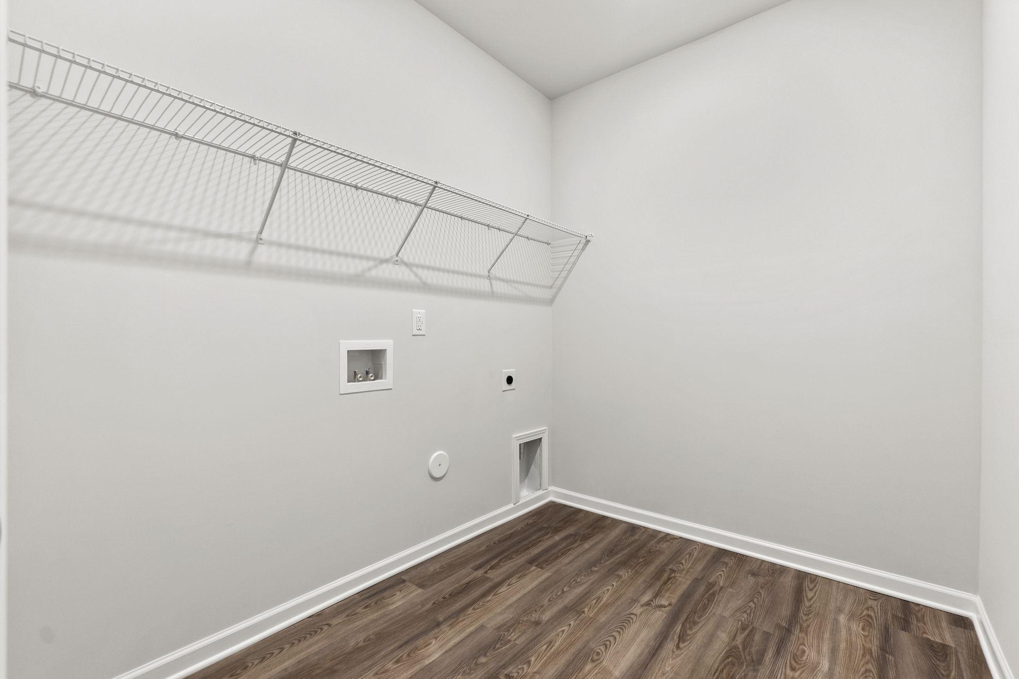 A room with a wood floor and a white wall with a white ceiling.