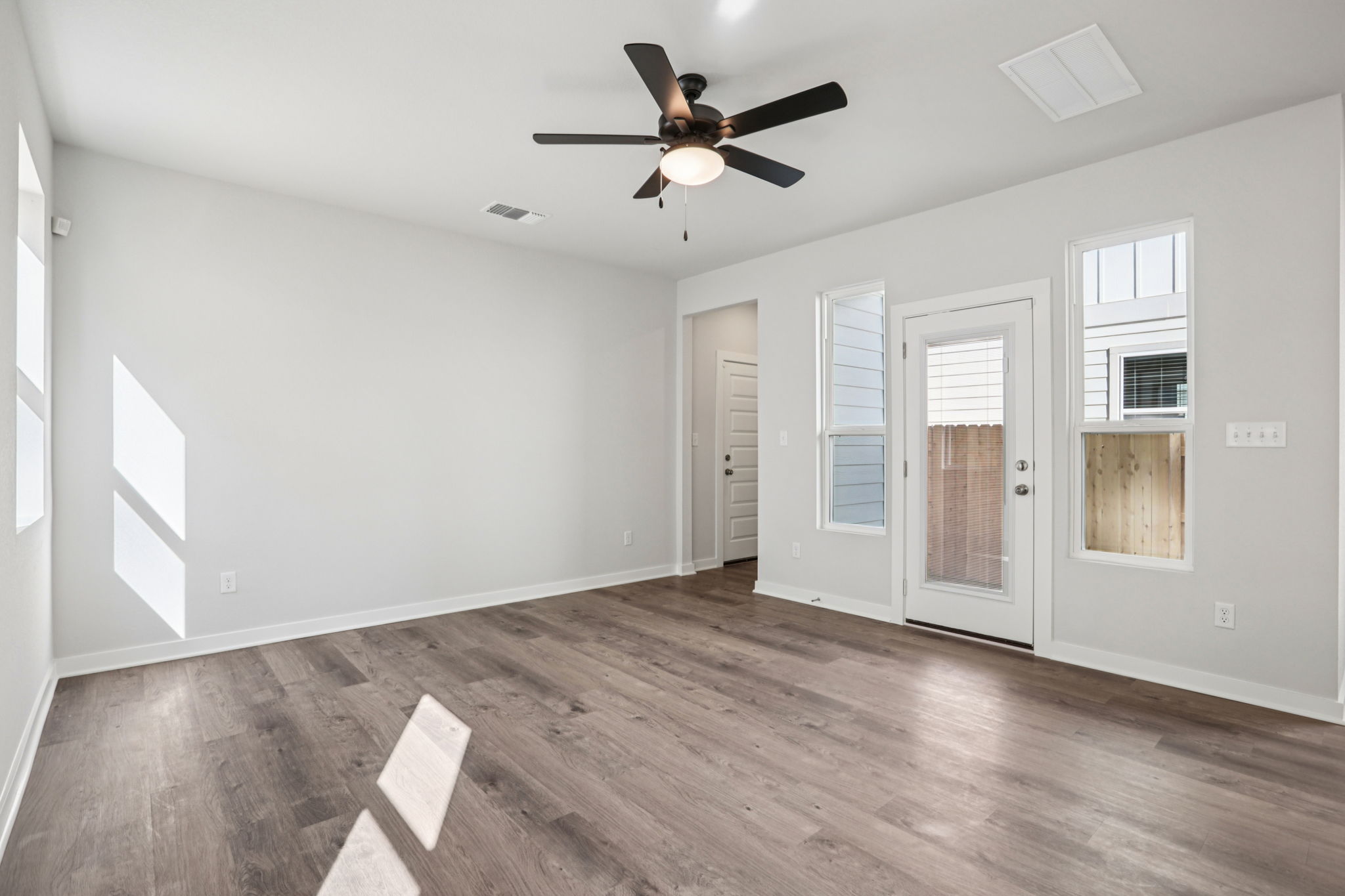 A room with a ceiling fan and a wood floor.