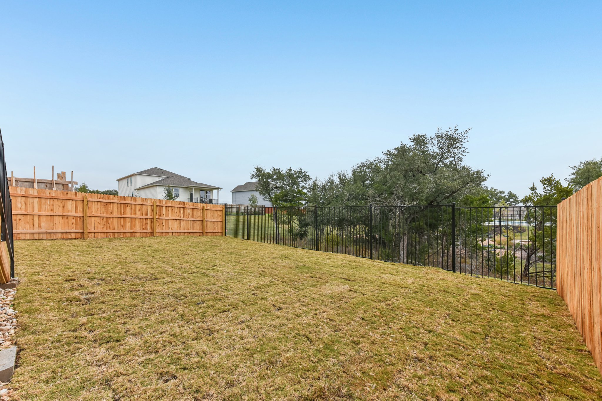 A fenced in yard with a tree and a house in the background.