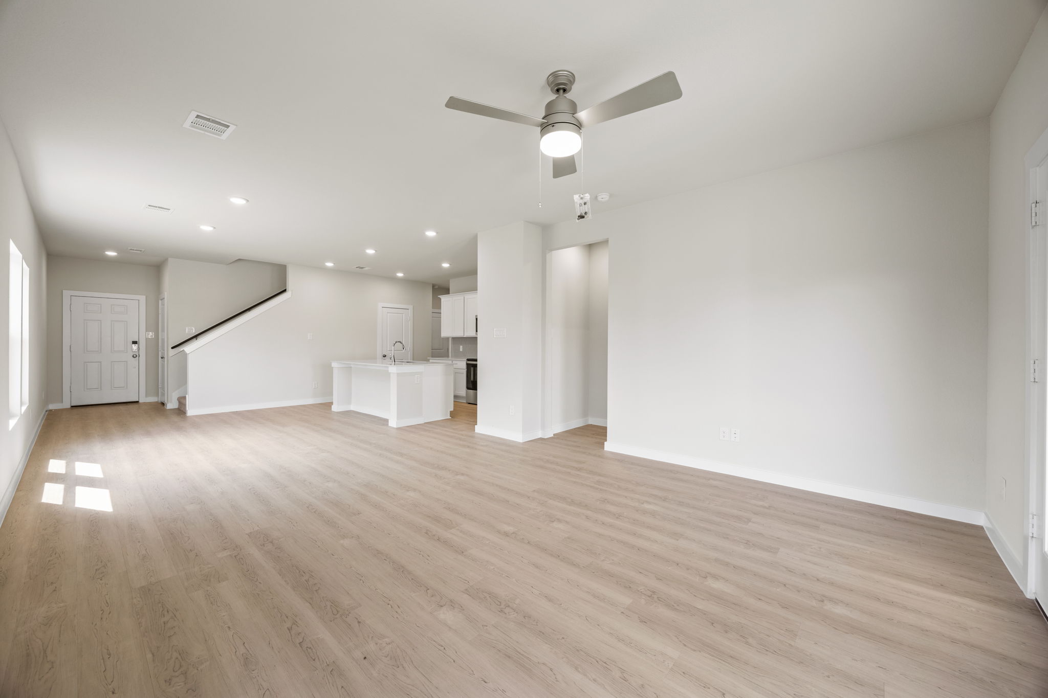 A large empty room with a ceiling fan and a wood floor.