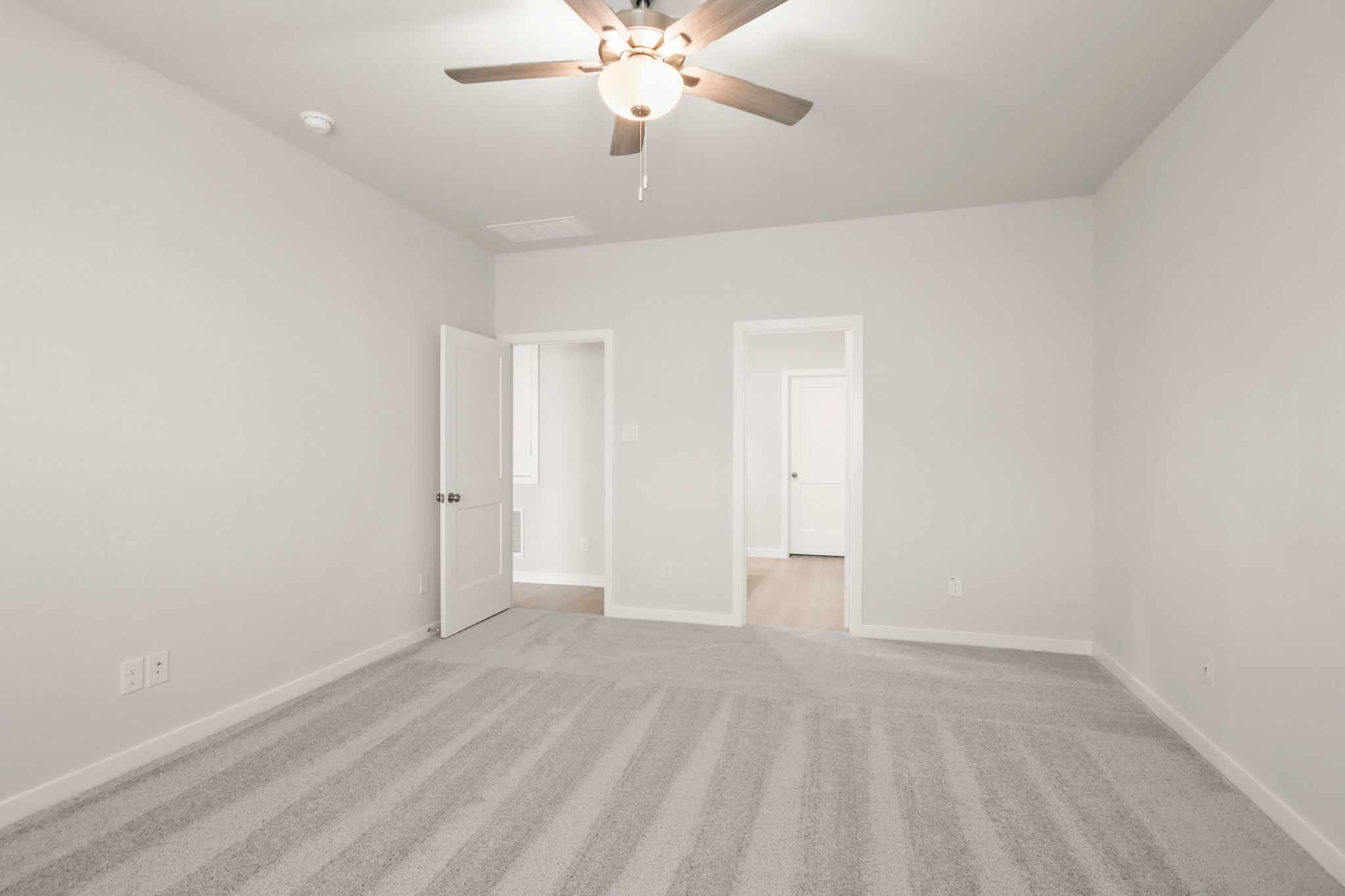 A room with a ceiling fan and white walls.