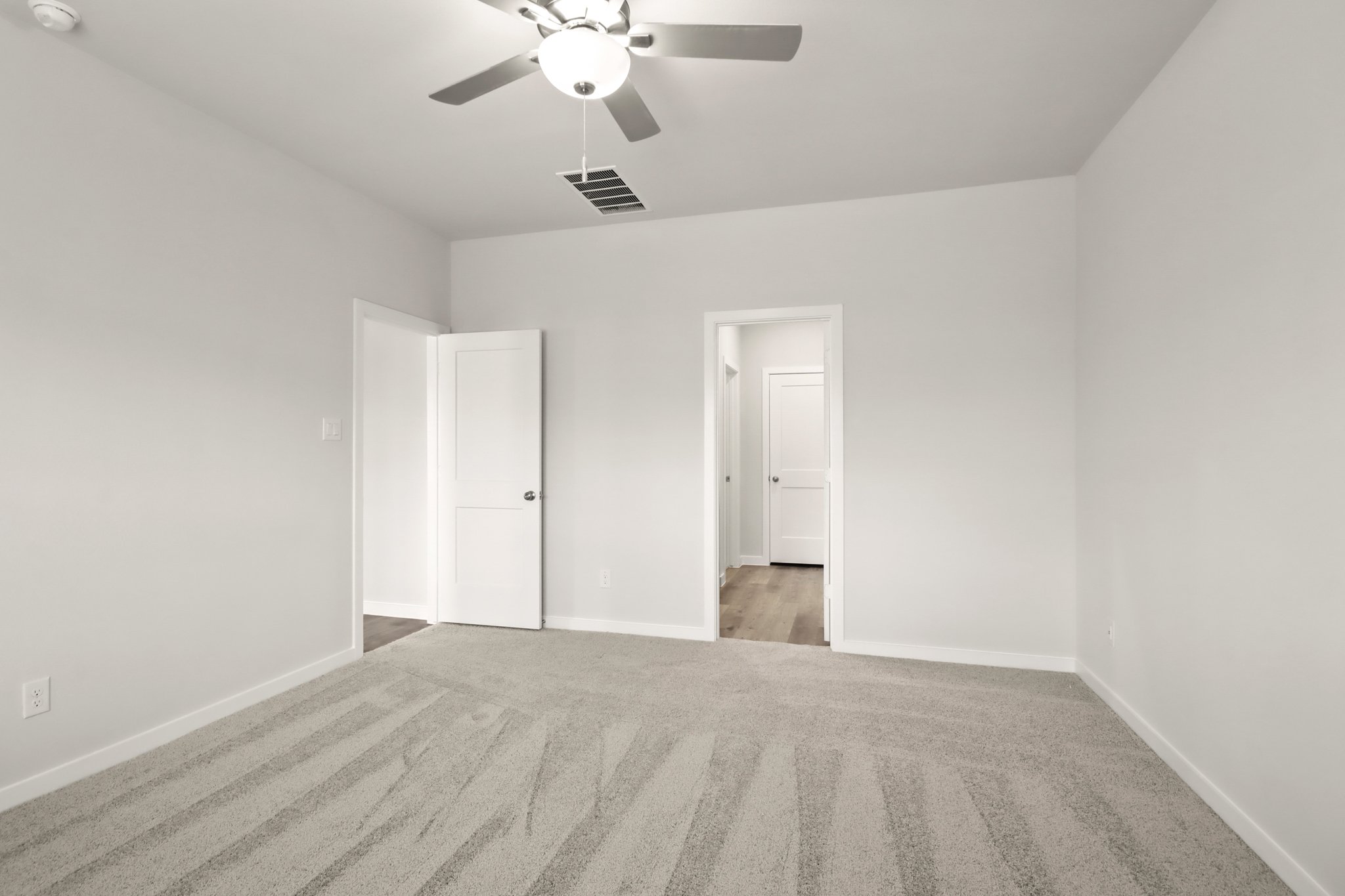 A room with a ceiling fan and a door.