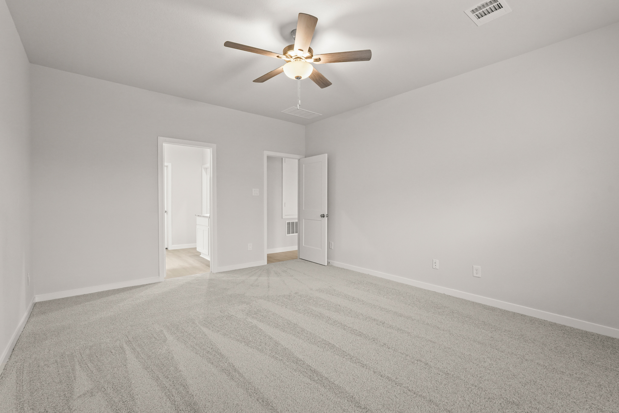A room with a ceiling fan and a carpet.
