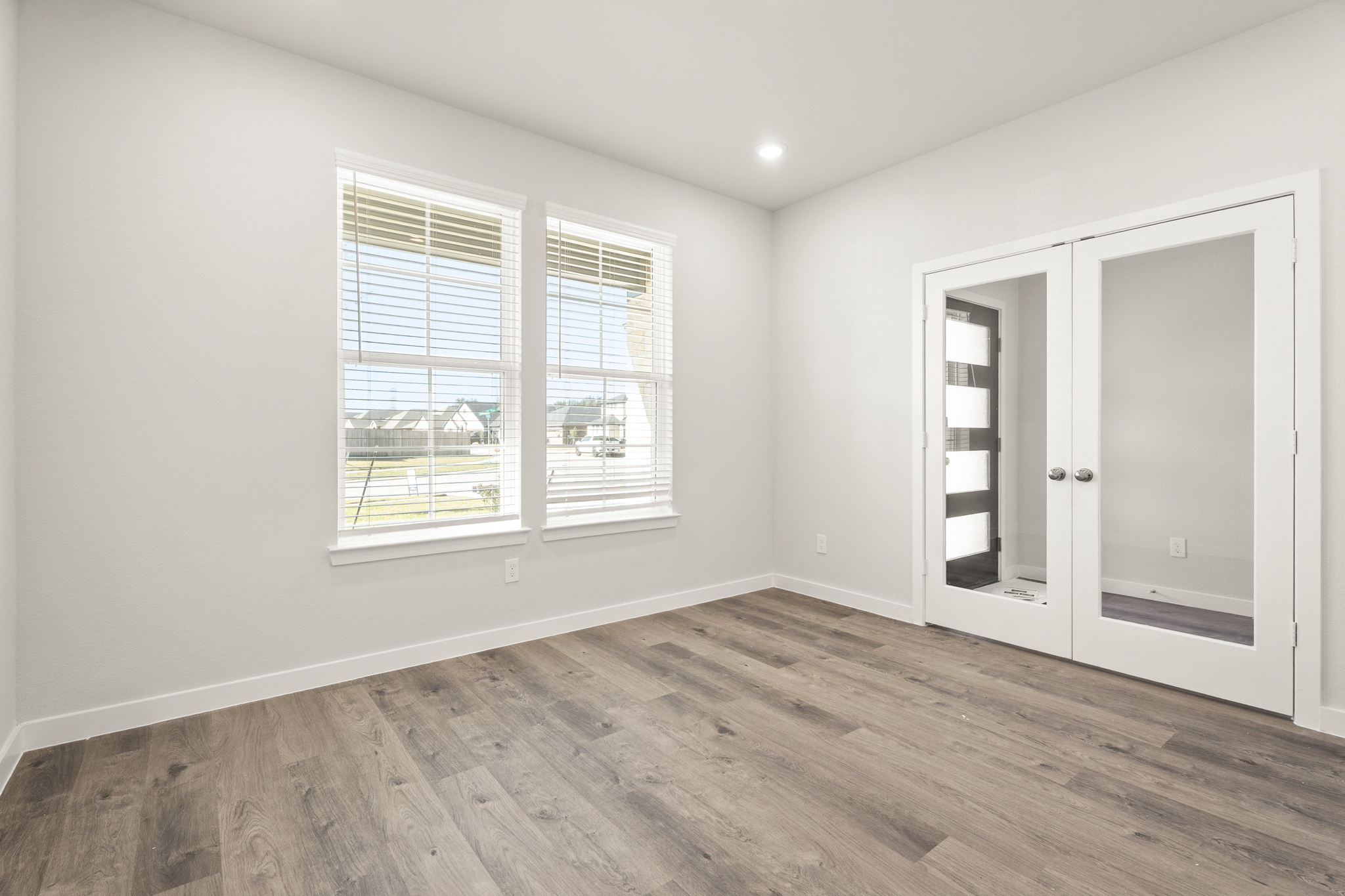 A room with a wood floor and a window with blinds.