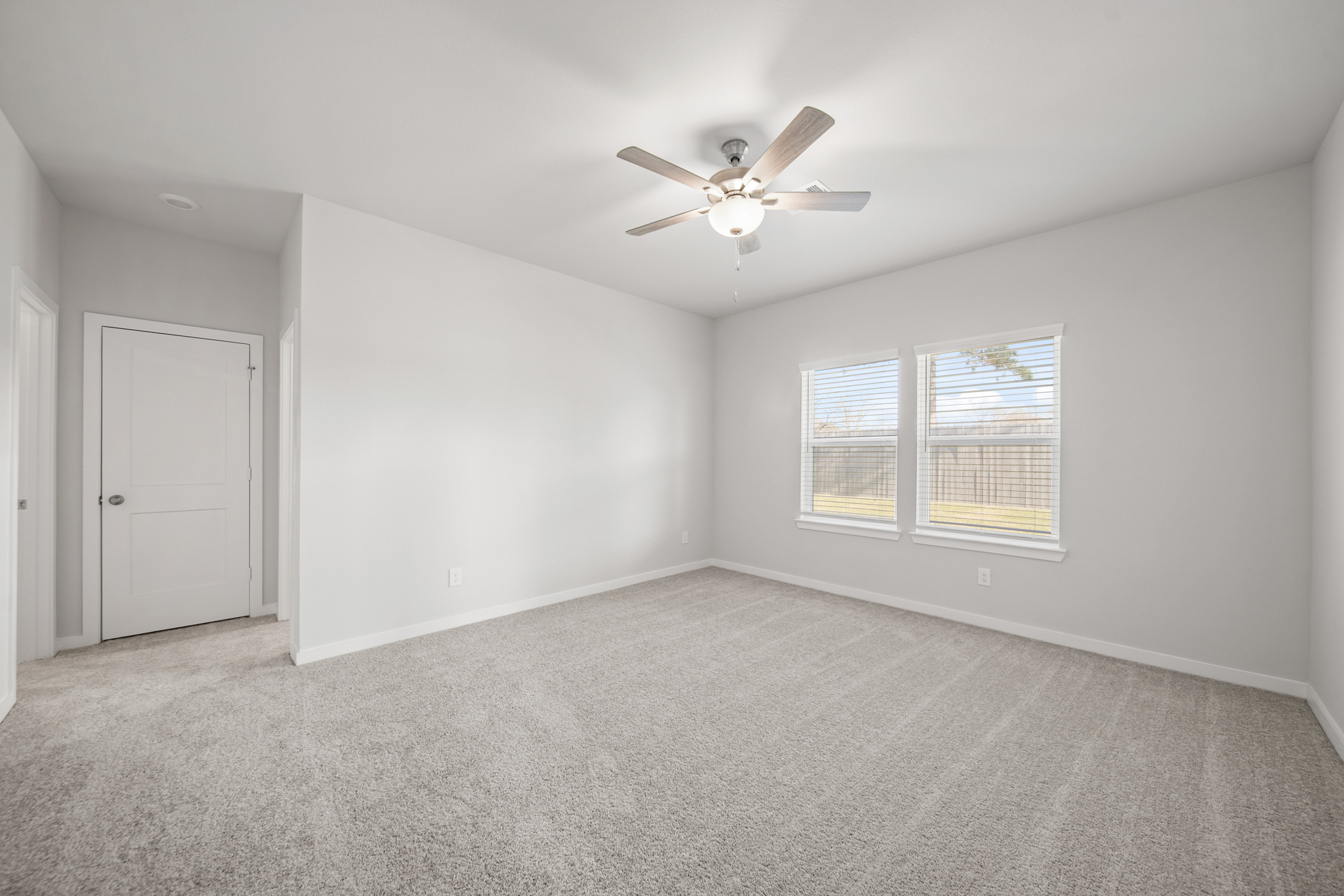 A room with a ceiling fan and a door.