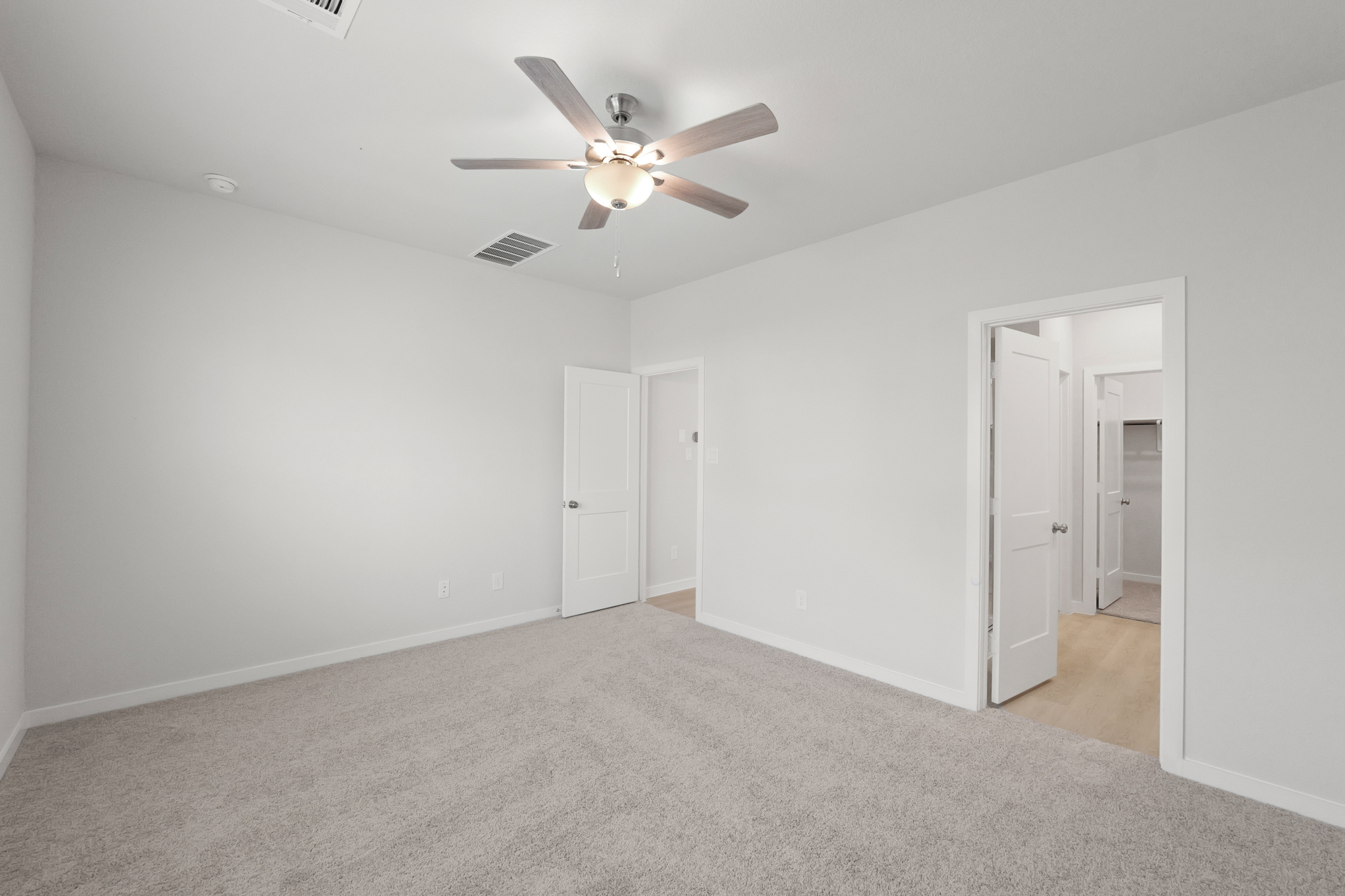 A room with a ceiling fan and a door.
