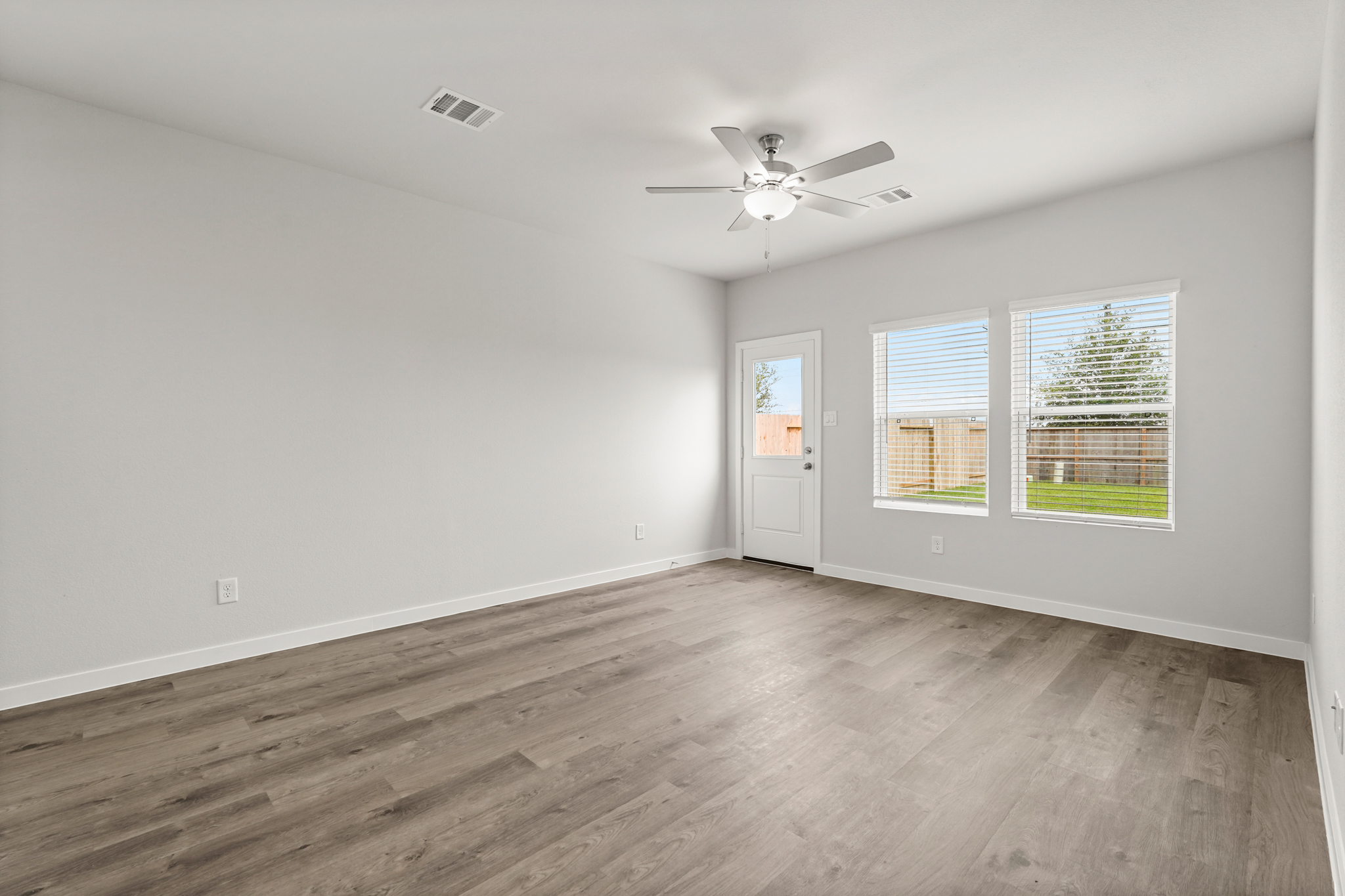 A room with a ceiling fan and a wood floor.