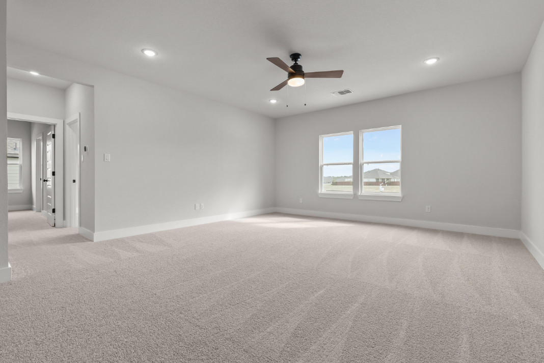 A room with a carpet and a ceiling fan.