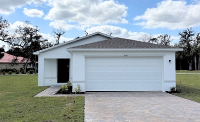 A white garage with a brick driveway.